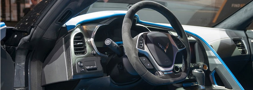 Interior view of a modern car dashboard with steering wheel and control panel.